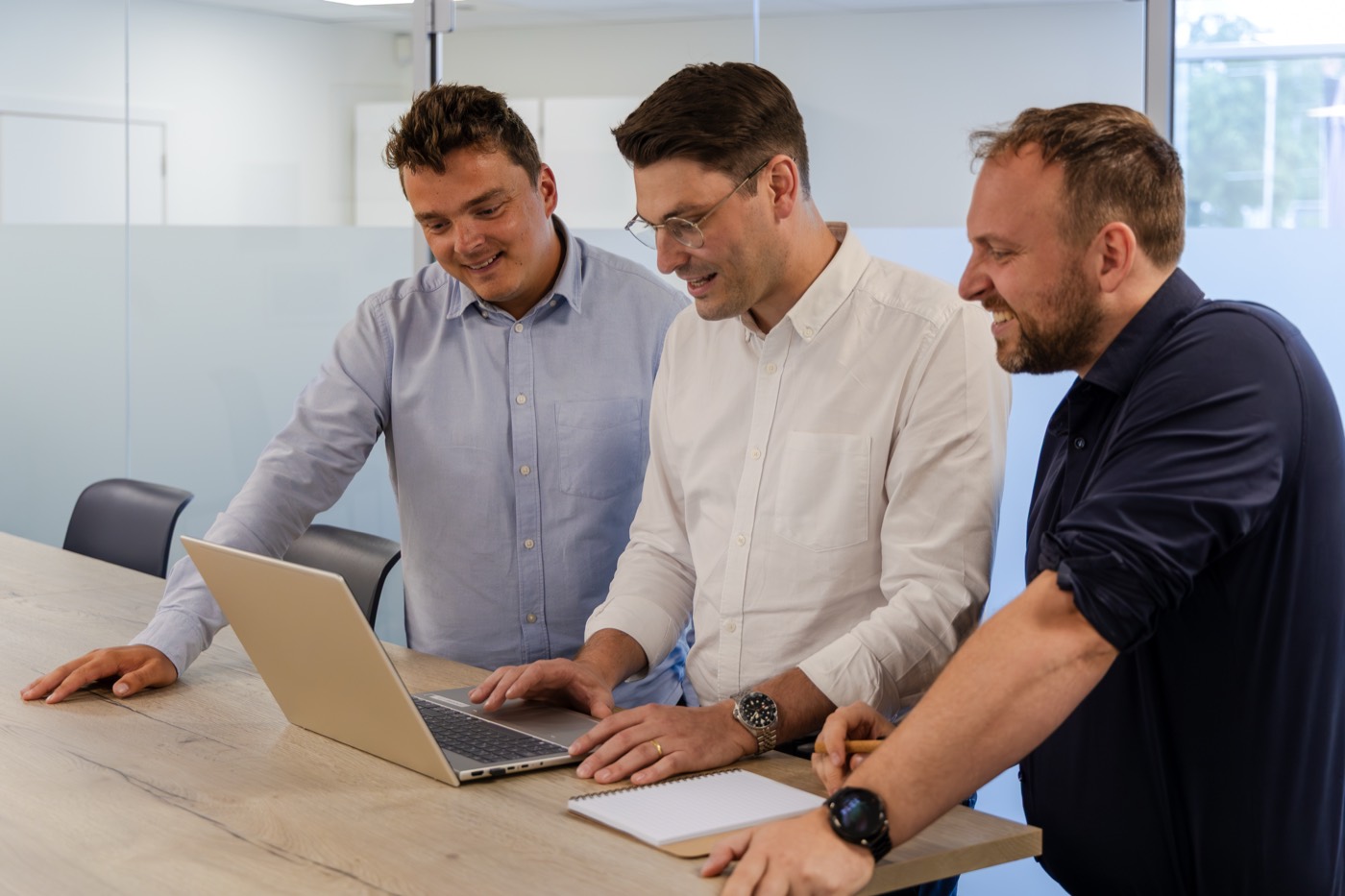 Vier collega's samenwerken rond een tafel met laptops